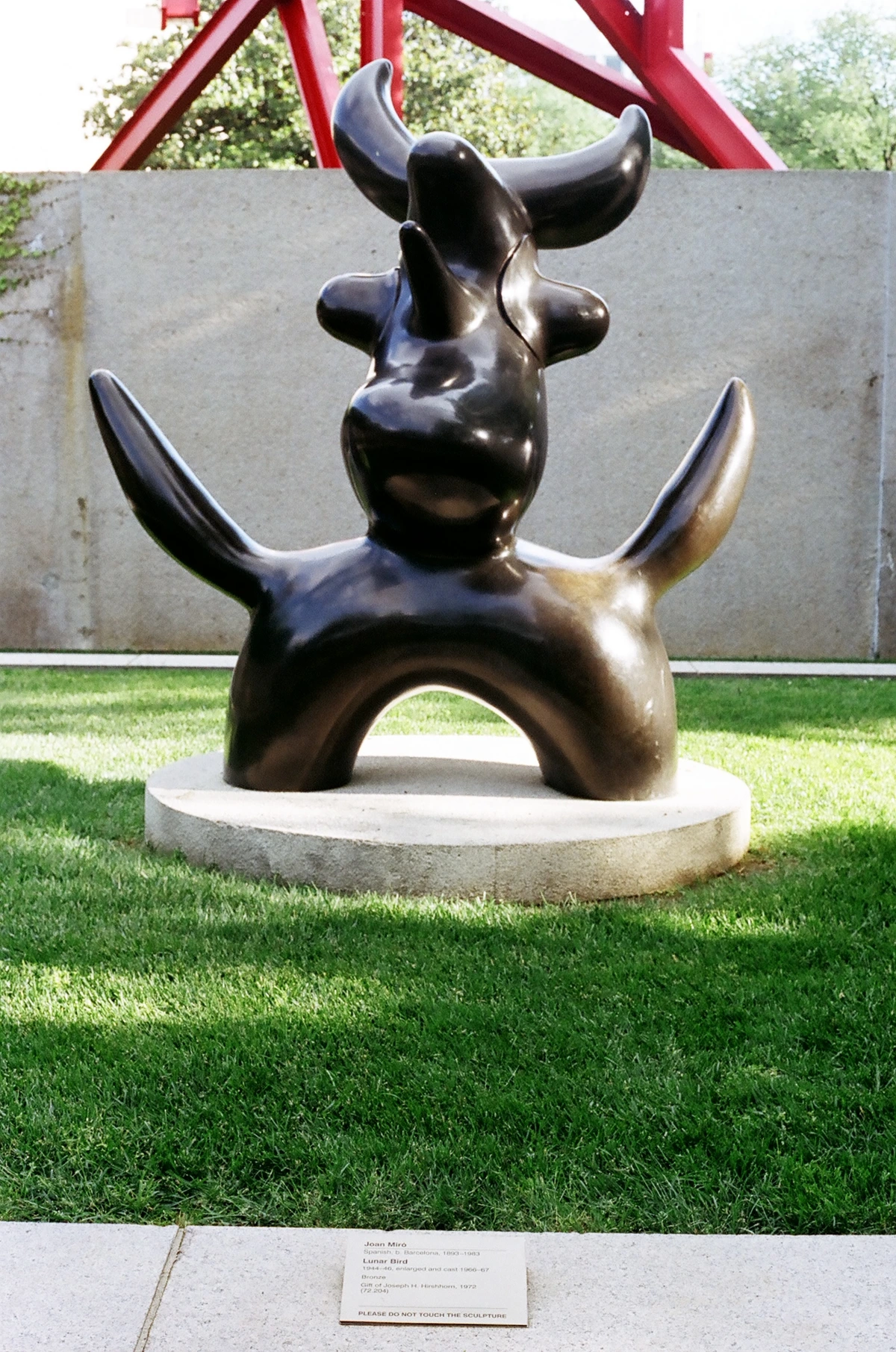 Joan Miró's bronze sculpture 'Lunar Bird' on a concrete pedestal in the Hirshhorn Sculpture Garden, showcasing a well-developed patina.