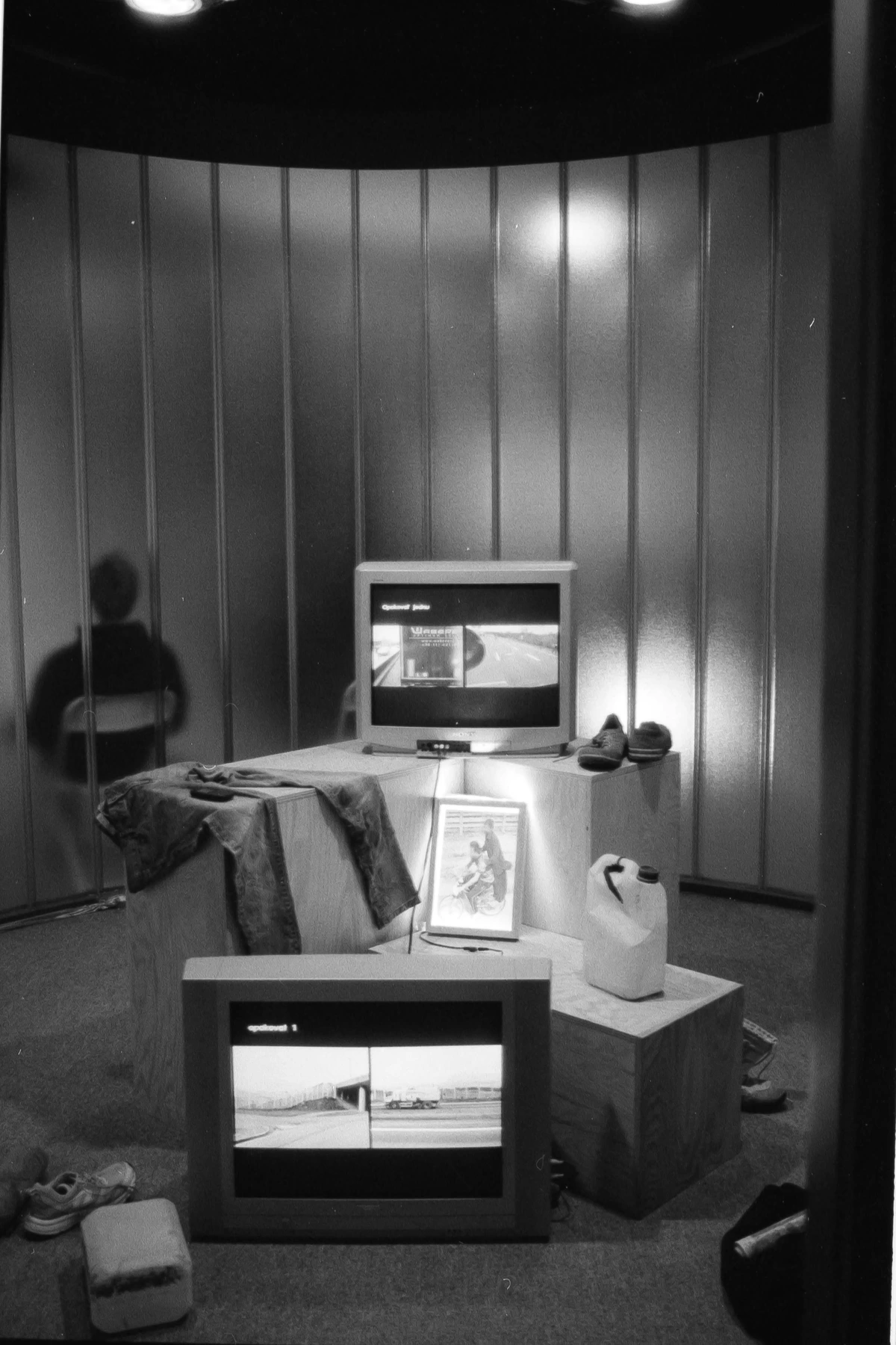 Art Installation Made from Old Television Screens and Clothing on a Wooden Platform in a Contemporary Exhibition