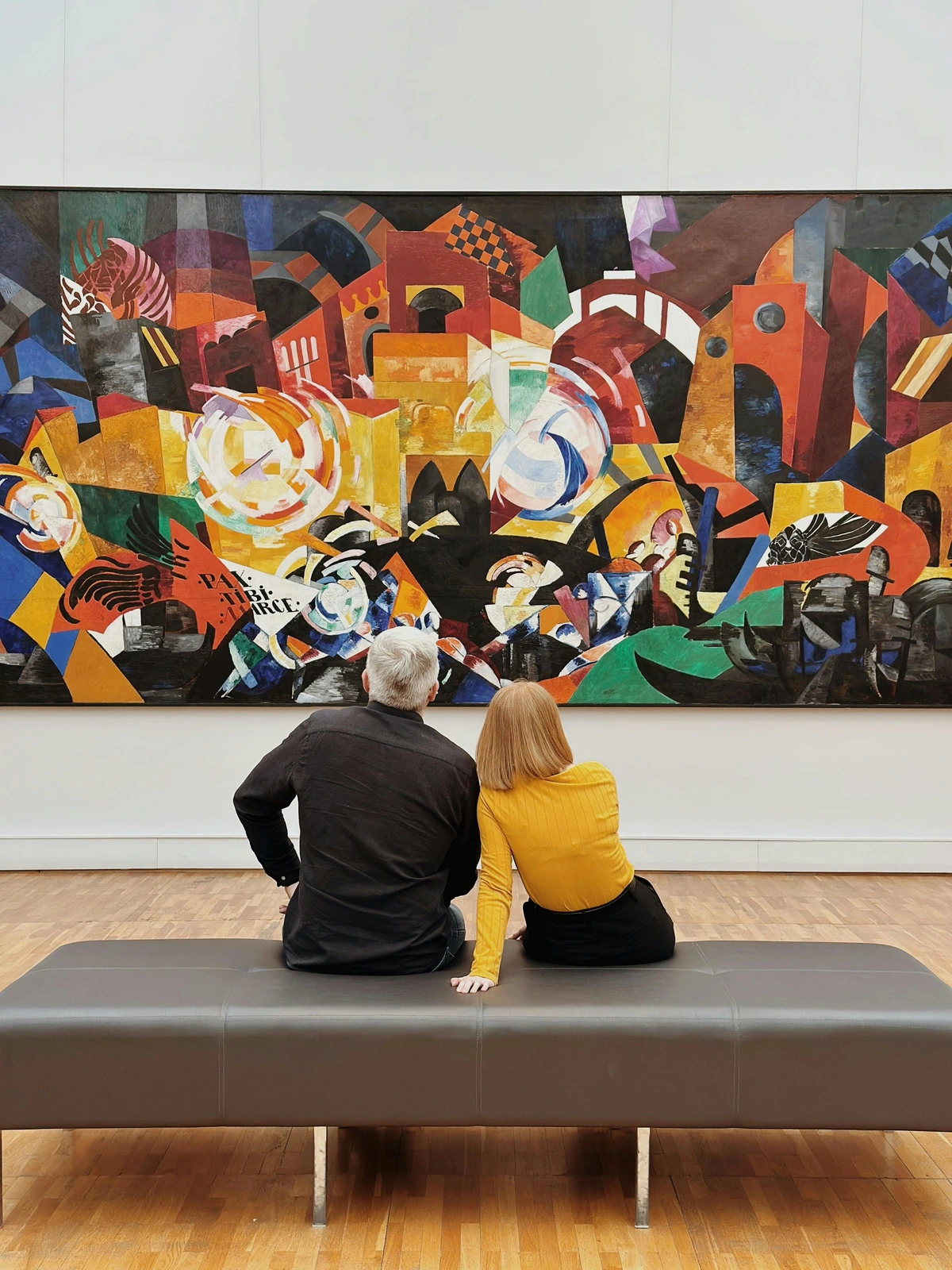 Two people gazing at a vibrant abstract painting in a contemporary art gallery.