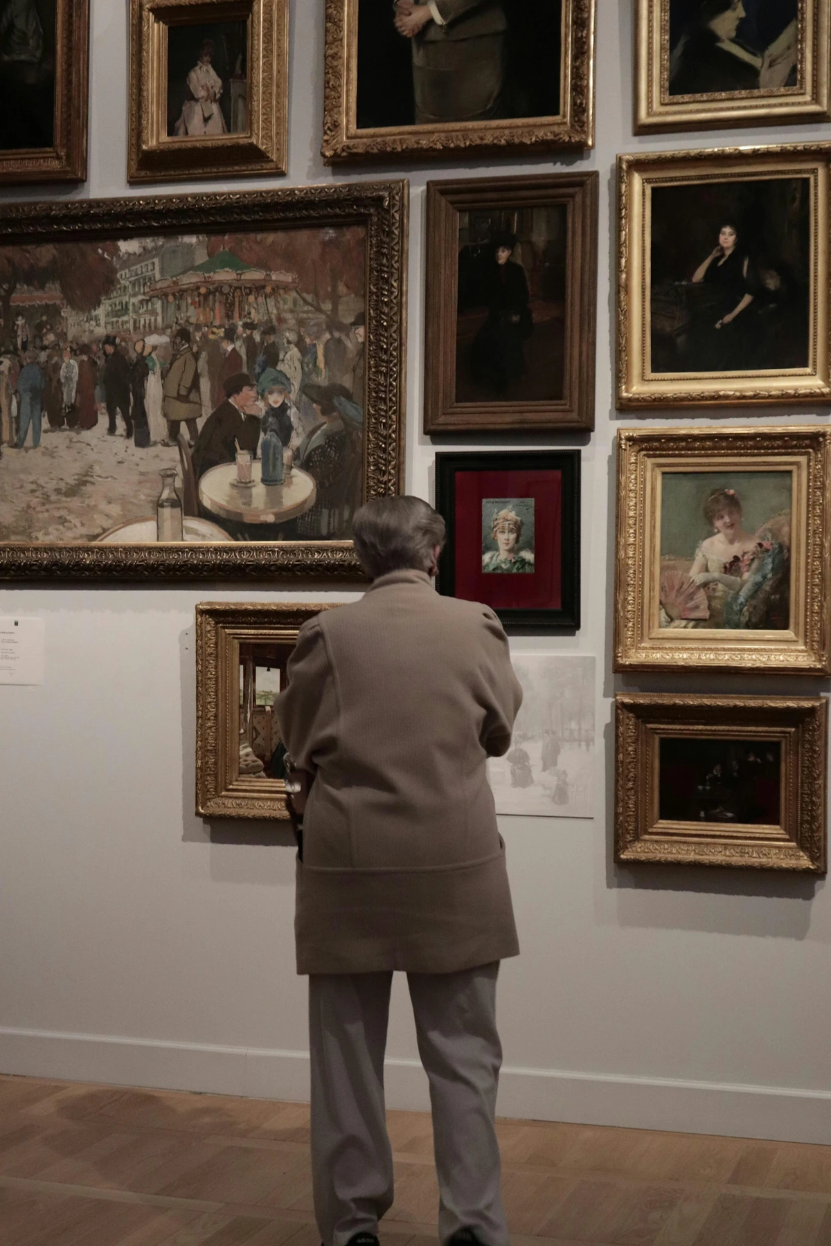 Back view of a visitor observing art within an art institution setting with framed galleries together depicting public art engagement with cultural heritage