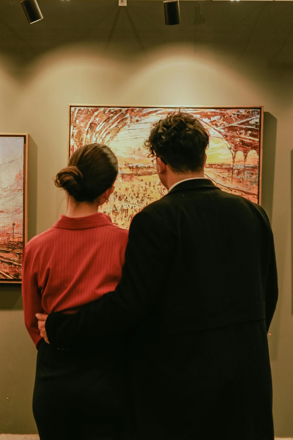 Woman and man observing an abstract painting in a museum exhibition hall, capturing the moment of art appreciation on a gallery walkthrough.