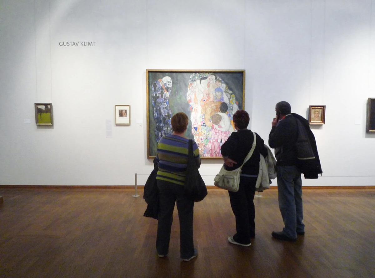 Visitors in a gallery compelling with Gustav Klimt's 'Death and Life'.