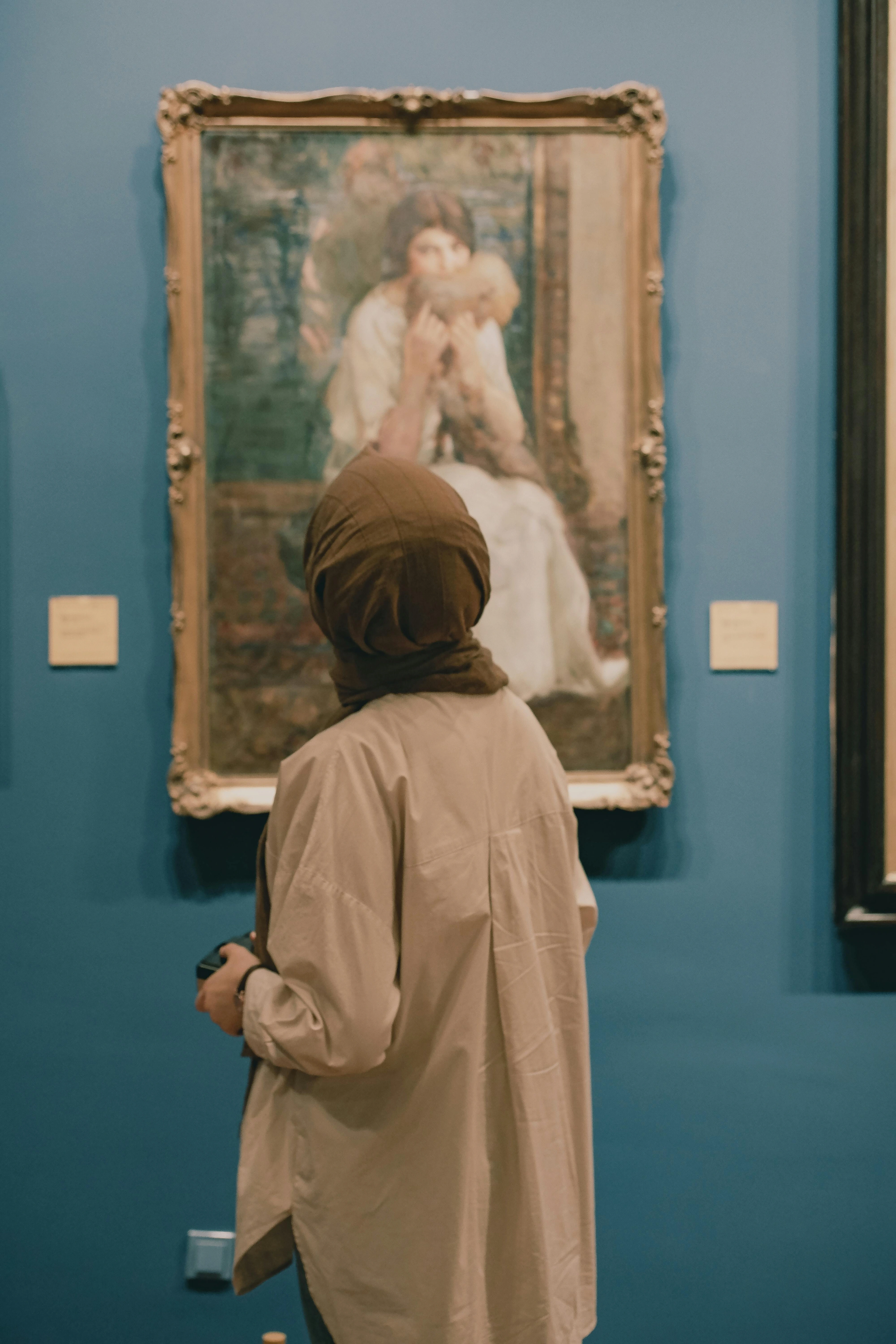 Woman observing intricate painting in museum exhibition space