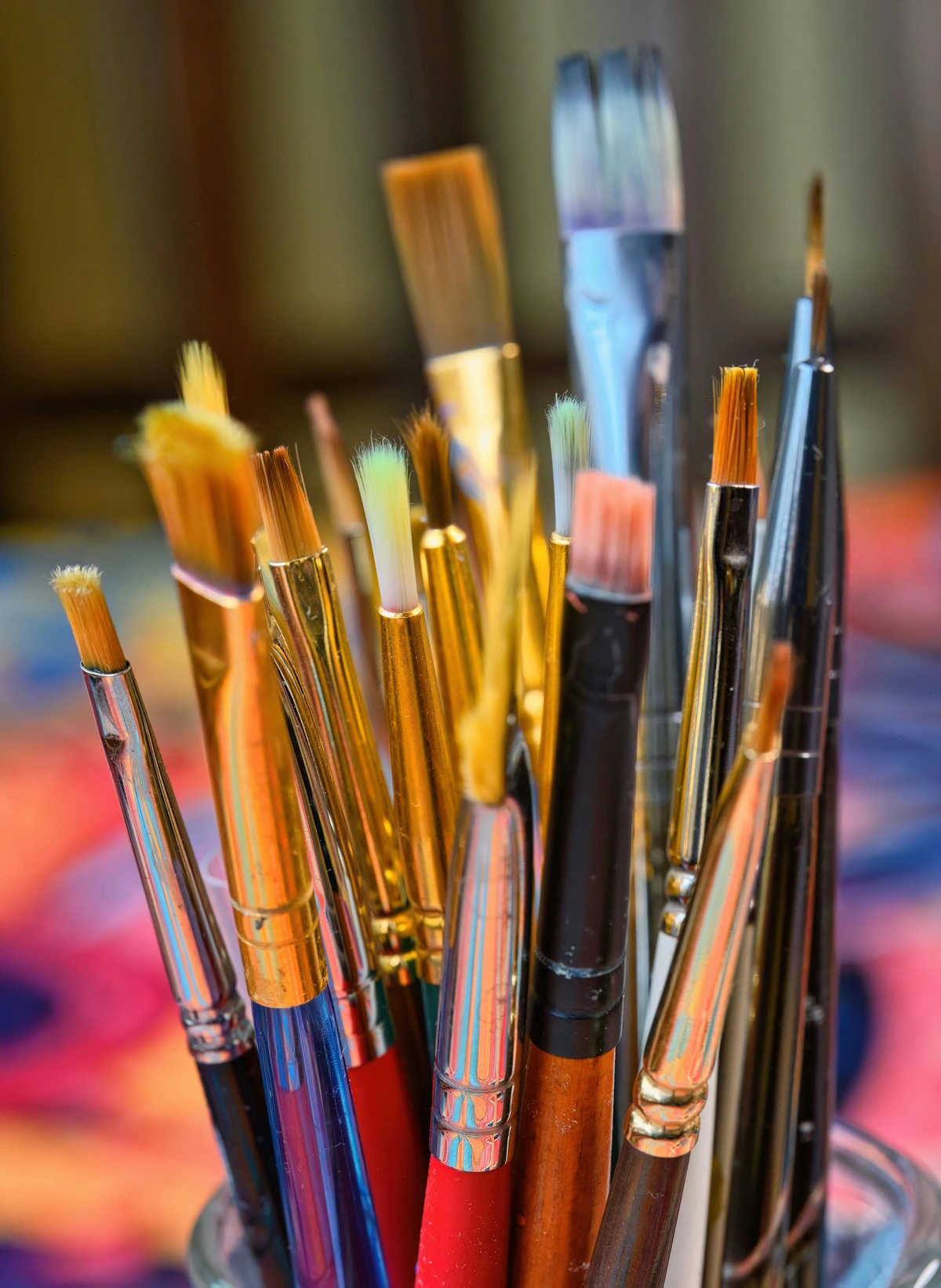Colorful array of paint brushes organized in glass jar for artistic purposes