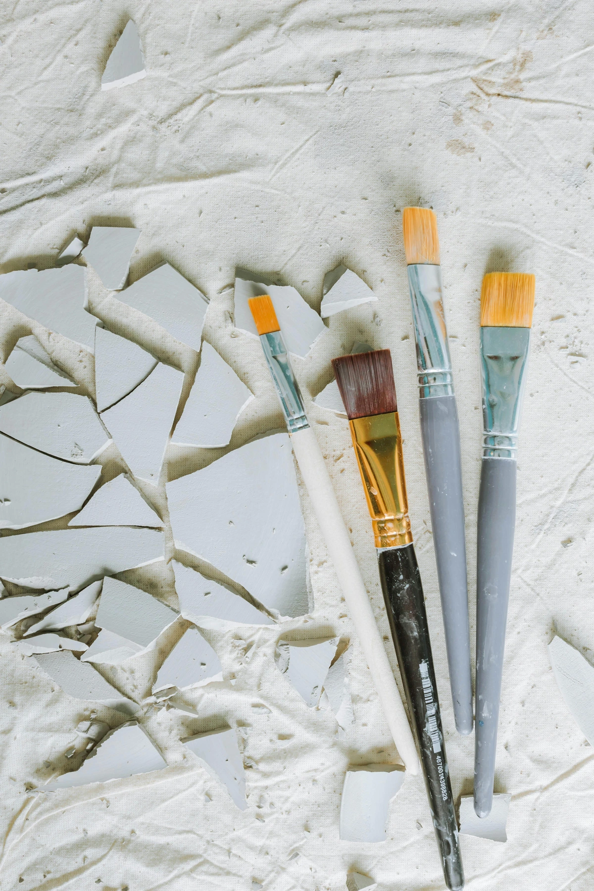 Synthetic art brushes on white textured surface with paint splatters, isolated for clarity and detail