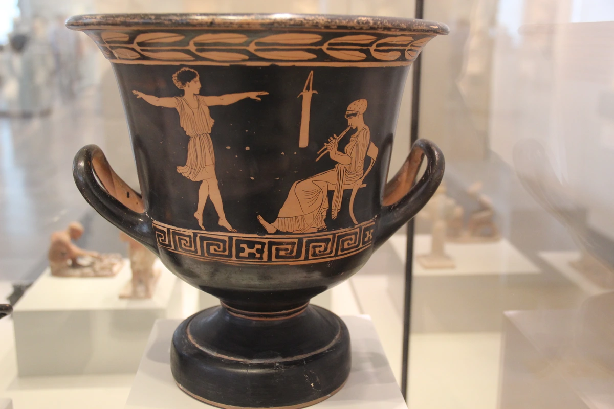 Ancient Greek red-figure ceramic calyx crater depicting a girl dancing and a musician playing the flute.