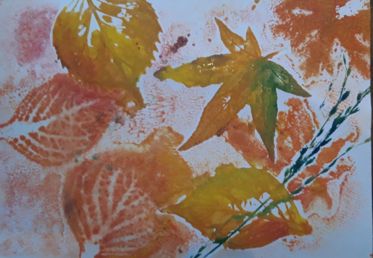 A monoprint artwork featuring various autumn leaves in shades of orange, yellow, and green, with visible leaf veins and textures.