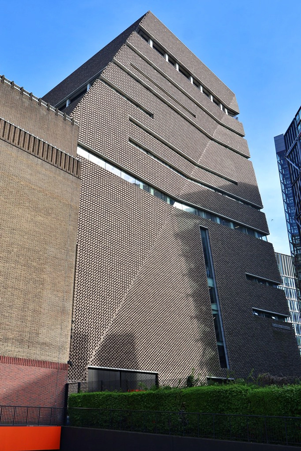 The distinctive brick facade of the Tate Modern's Switch House extension in London, featuring geometric patterns and angular design.