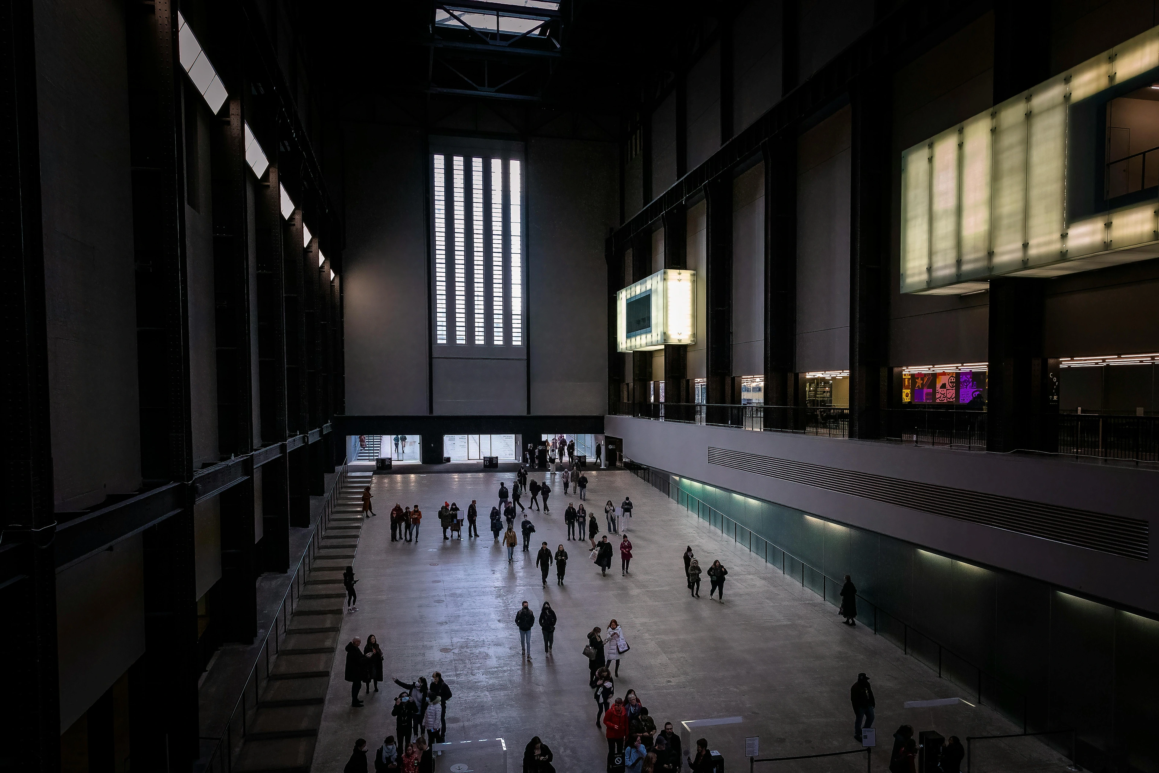 Expansive interior of the Tate Modern art gallery in London, showcasing its vast Turbine Hall with visitors exploring the space.