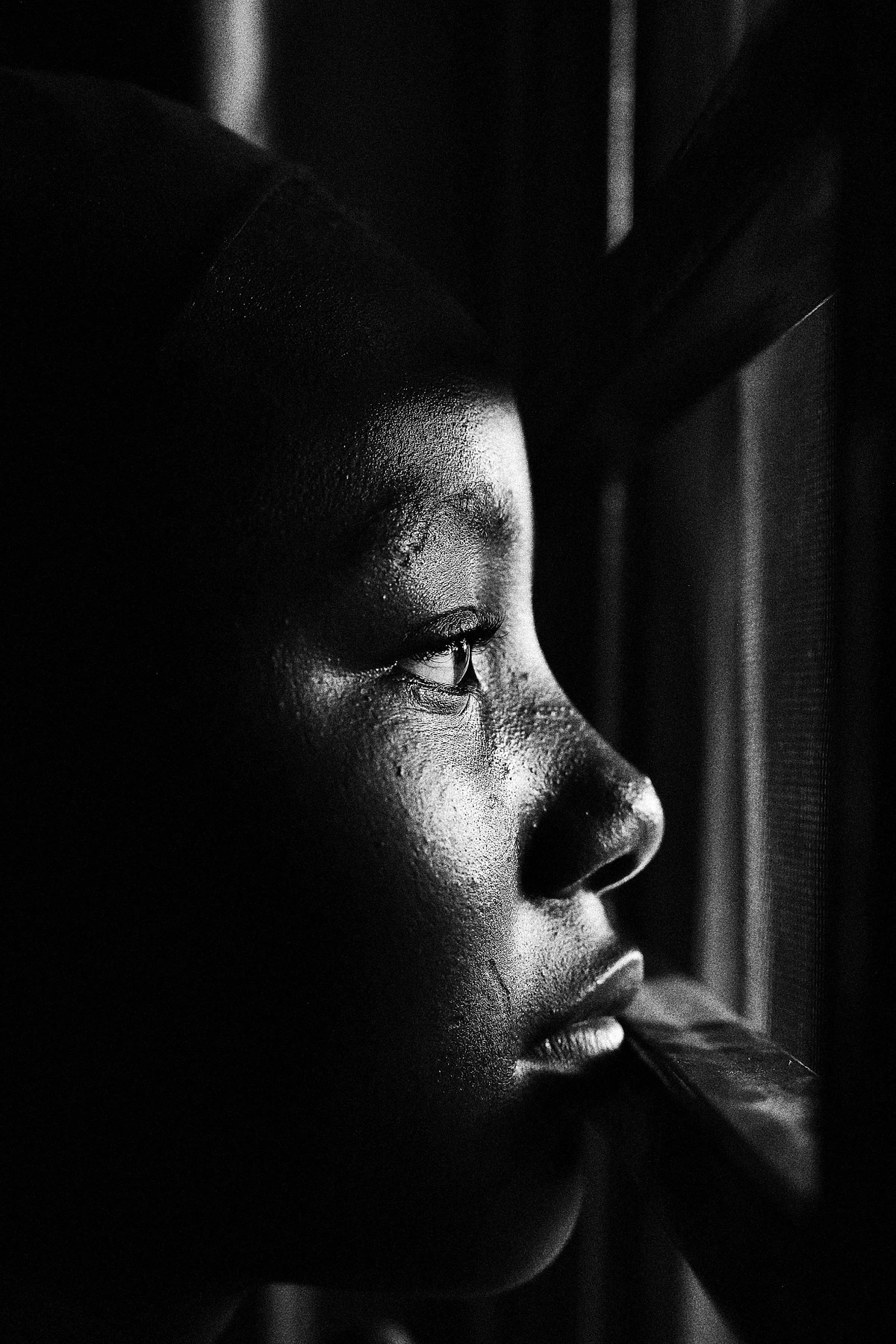 Close-up of a child's face in profile, with one side illuminated by sunlight and the other in shadow, highlighting the texture of the skin and the eye, serving as a clear example of chiaroscuro's ability to model form.