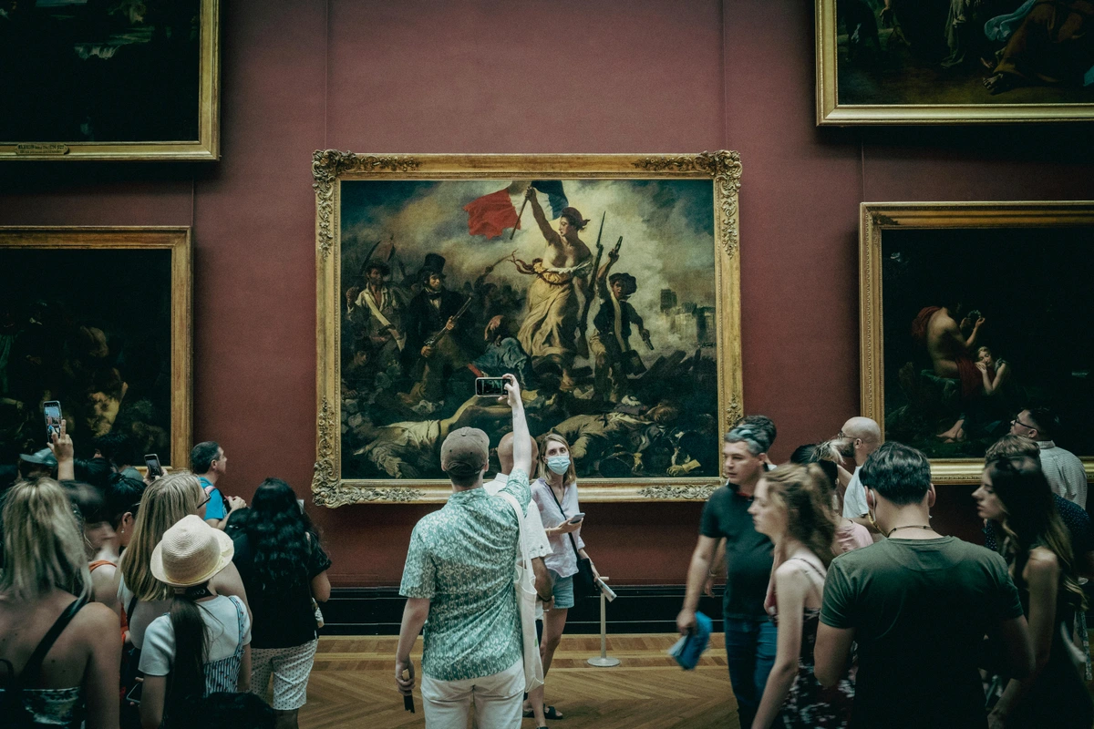 People admiring art at the Louvre Museum, featuring the Mona Lisa and Egyptian antiquities, ideal for exploring art criticism and cultural heritage topics