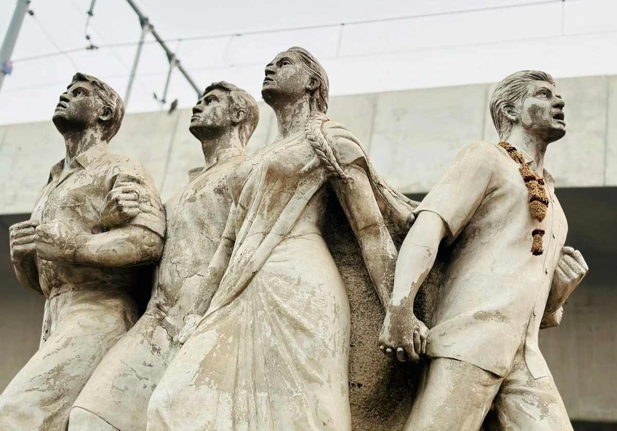 People holding hands in a white statue carved with cracked paint, symbolizing unity
