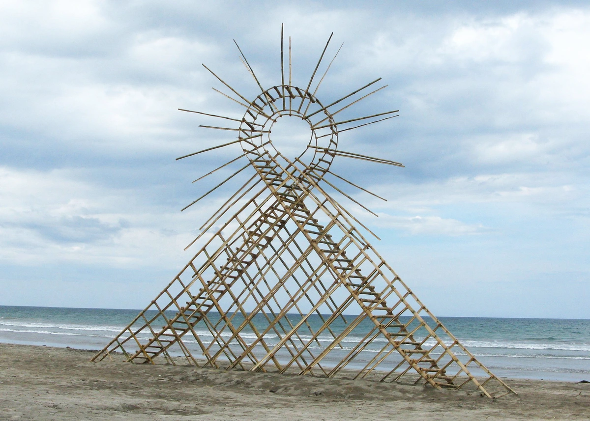 Tanya Preminger's 'Air loop' land art installation on a sandy beach, with the ocean and cloudy sky in the background.