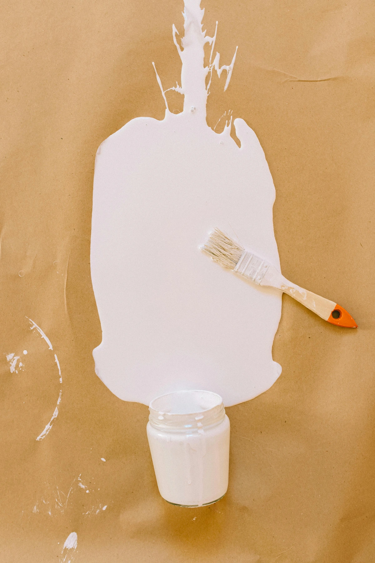 A white plastic brush on brown paper showing an art project with masking tape