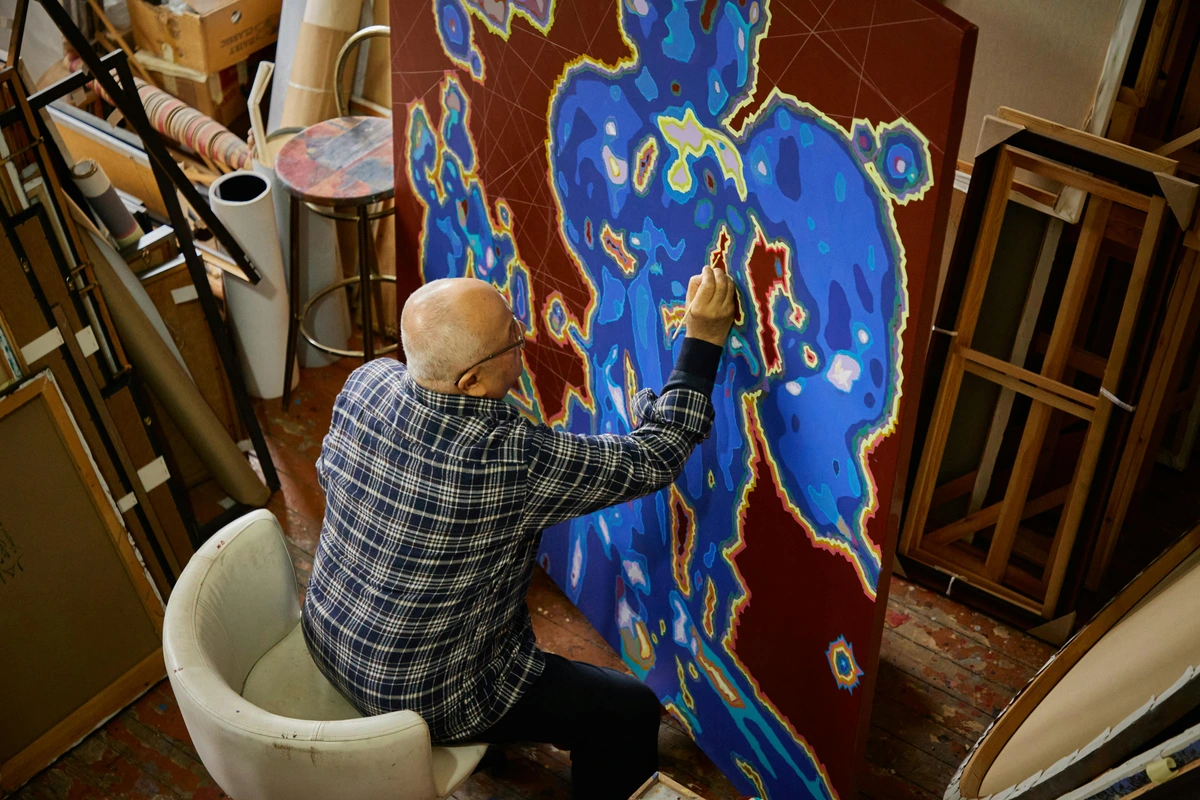 Artist creating abstract painting using painters tape art techniques in studio