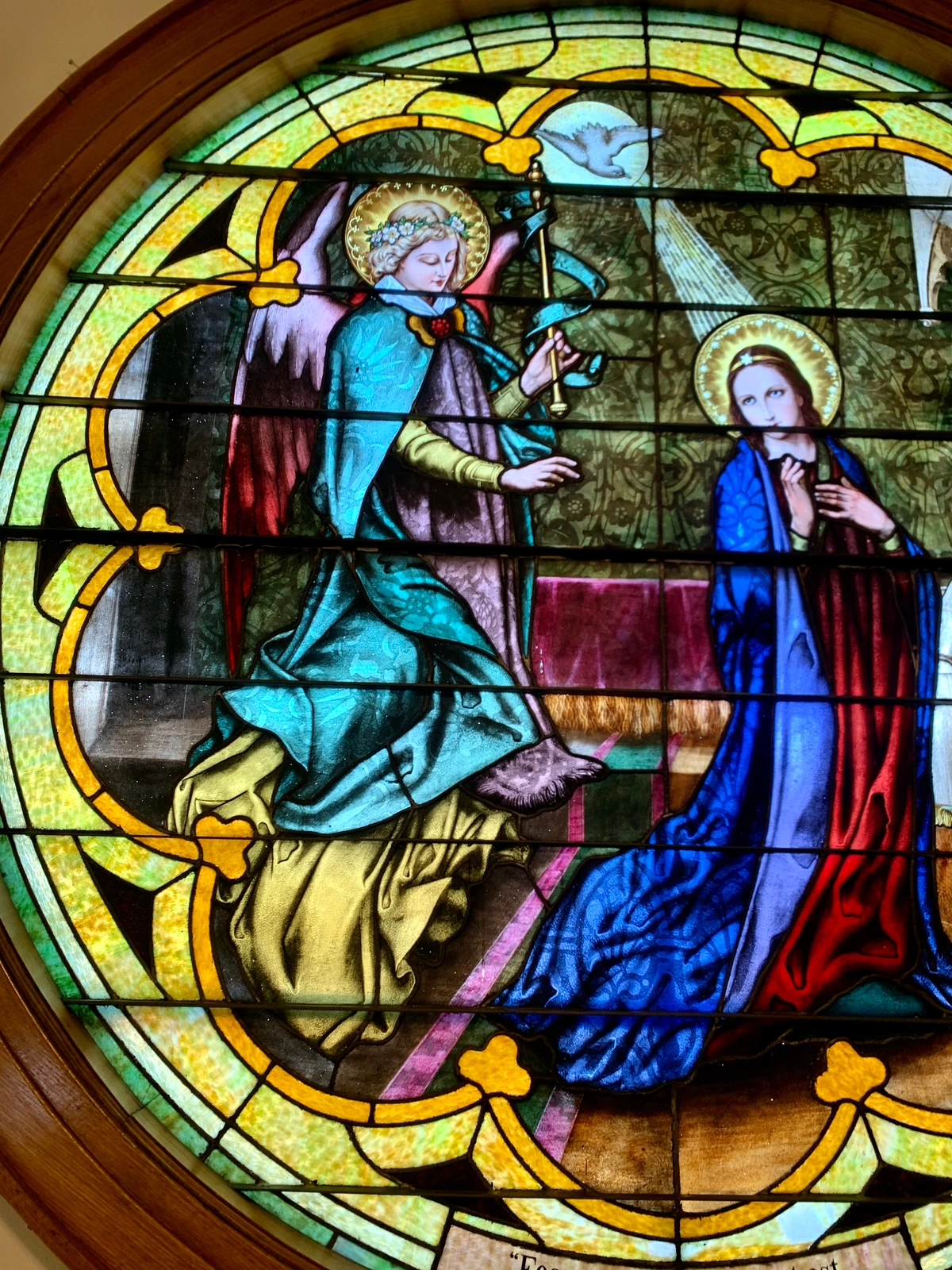 Close-up of a stained glass window depicting the Annunciation, with Angel Gabriel and the Virgin Mary.