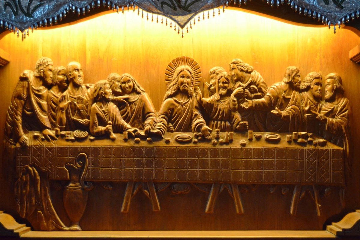 Detailed wood carving of the Last Supper, depicting Jesus Christ with his twelve apostles seated around a table.