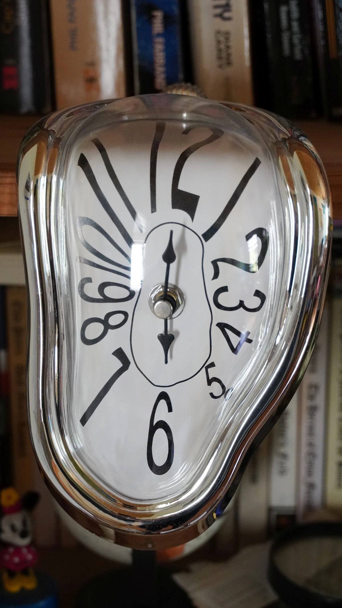 A melting clock in the style of Salvador Dali's 'The Persistence of Memory', with a silver frame and a white face showing black numbers and hands.