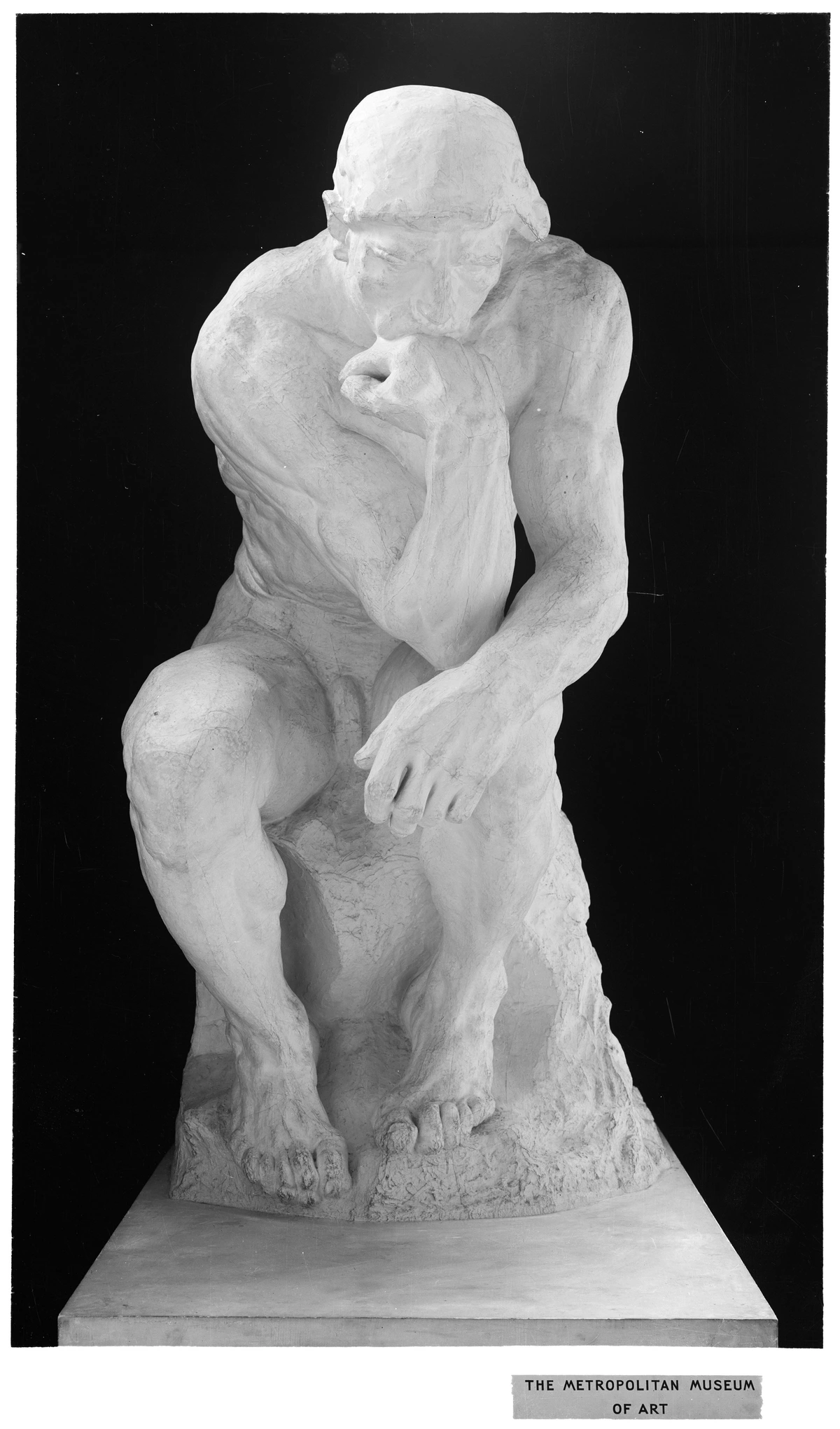 The Thinker sculpture by Auguste Rodin, a bronze statue of a nude male figure in deep contemplation, seated on a rock.