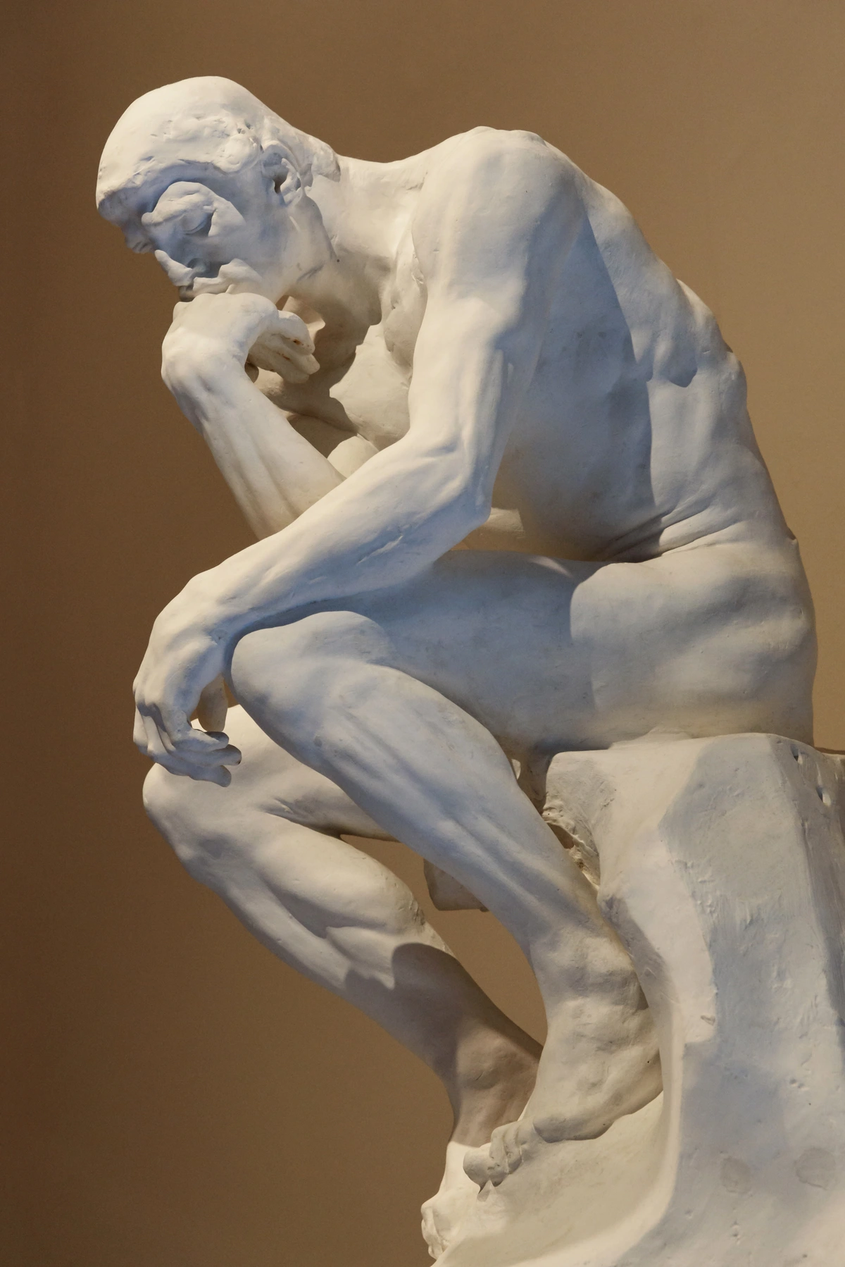 The Thinker sculpture by Auguste Rodin, a nude male figure in deep contemplation.