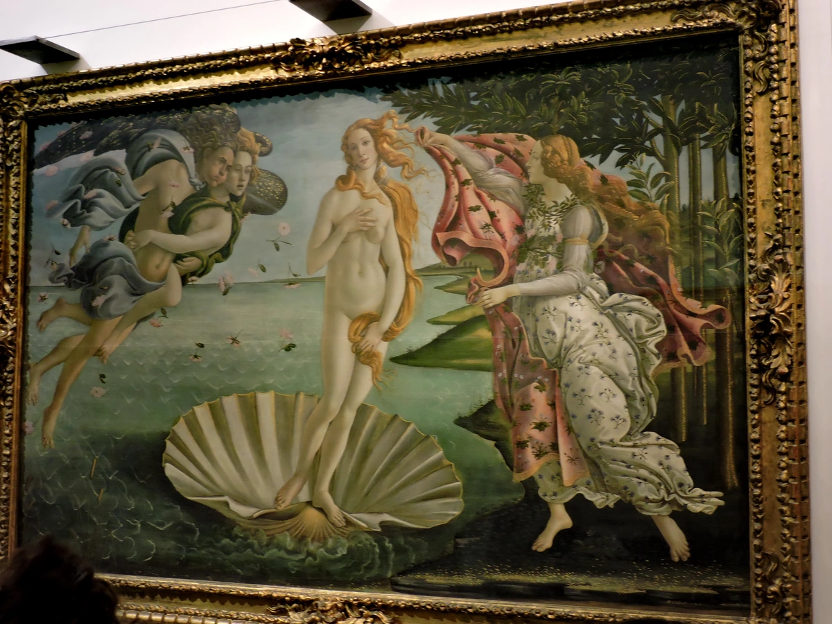 Sandro Botticelli's The Birth of Venus painting, depicting the goddess Venus arriving ashore on a seashell, blown by Zephyr and greeted by a Hora of Spring.