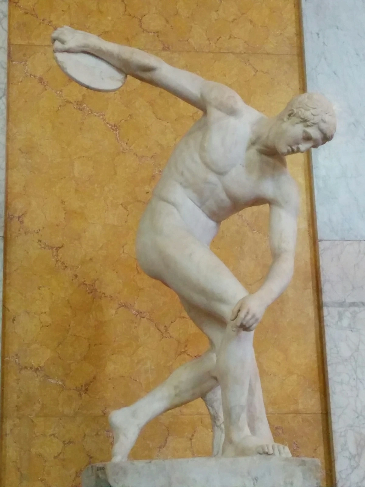 Side view of the Discobolus statue, an ancient Greek sculpture depicting an athlete in the motion of throwing a discus.