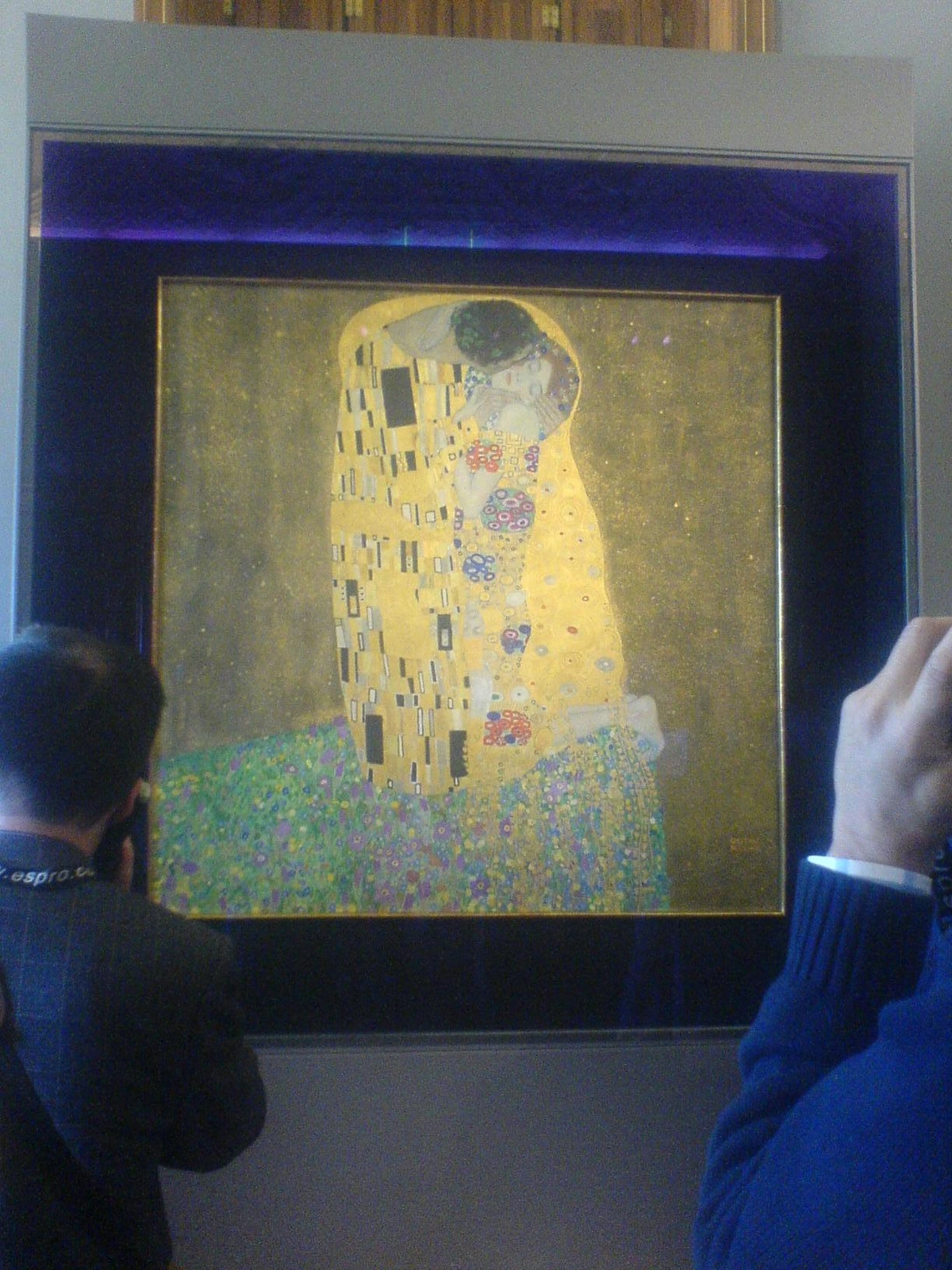The Kiss by Gustav Klimt, an iconic Art Nouveau painting depicting a couple embracing in a golden, patterned robe against a floral meadow.