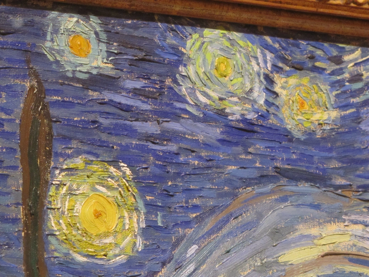 Detail van Van Goghs Sterrennacht schilderij met wervelende gele sterren en een donkere cipres tegen een blauwe nachtelijke hemel.