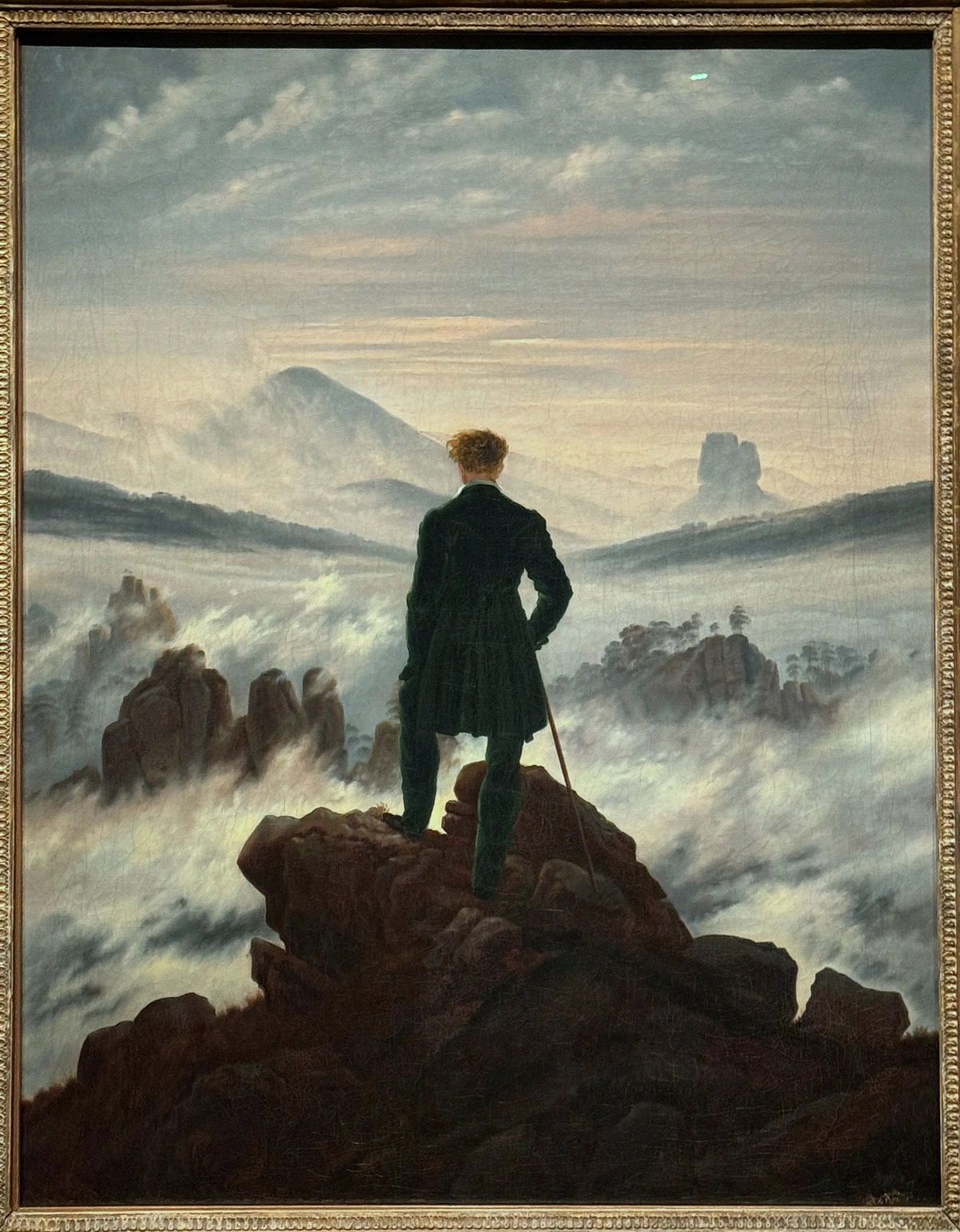 Caspar David Friedrich's Wanderer above the Sea of Fog, a man in a dark coat stands on a rocky precipice overlooking a vast, misty mountain landscape.