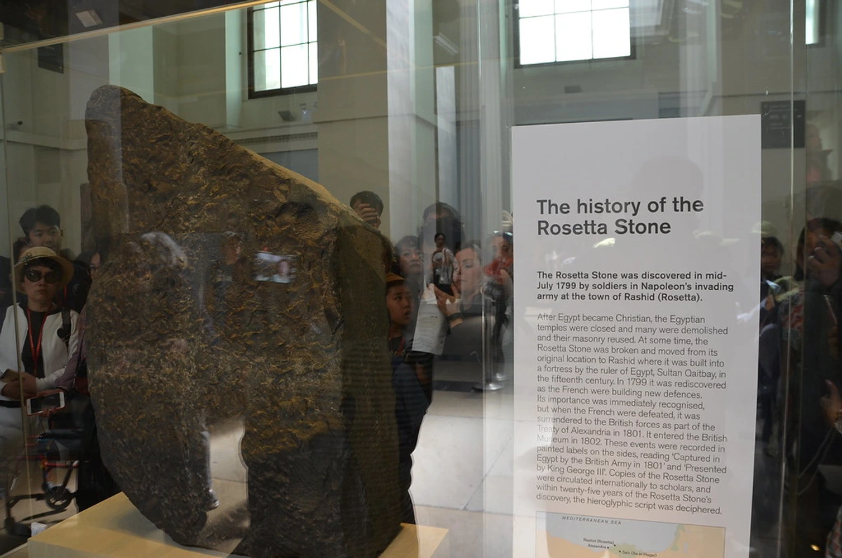 The history of the Rosetta Stone exhibit at the British Museum, with visitors viewing the artifact behind glass.