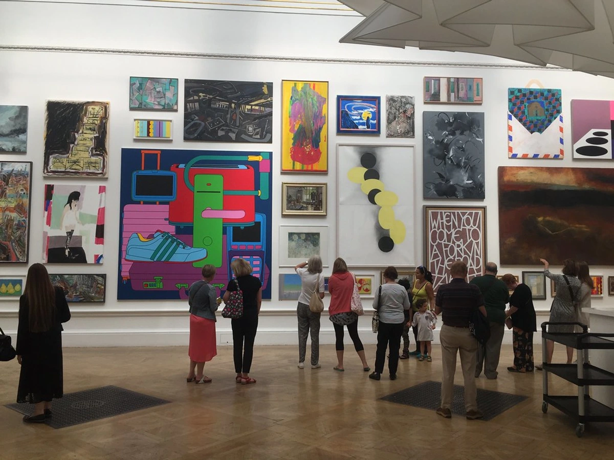 Visitors admiring diverse artworks at the Royal Academy Summer Exhibition, featuring paintings, installations, and sculptures.
