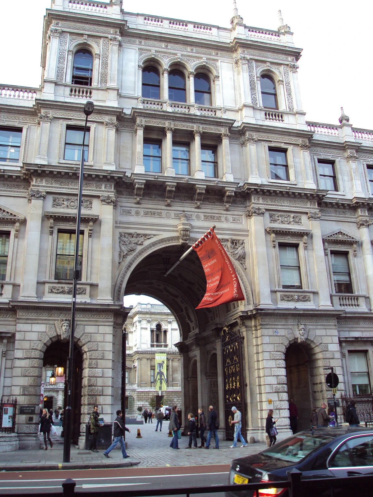 Burlington House, home of the Royal Academy of Arts on Piccadilly, London, with its grand archway and red banner.