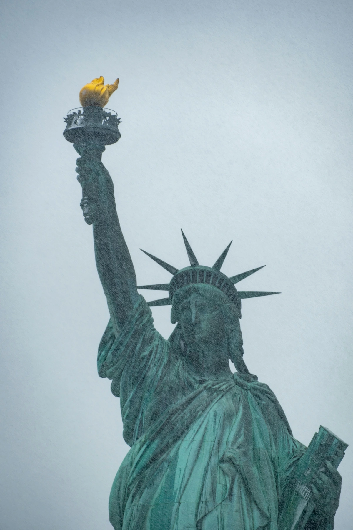 Statue of Liberty in winter mist with its golden torch illuminated