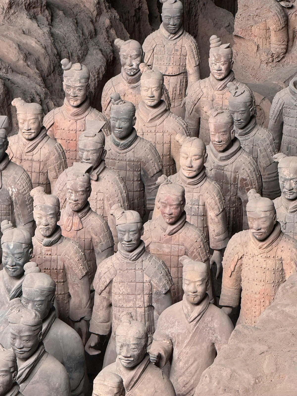 A close-up view of numerous life-size terracotta warrior statues from the Terracotta Army in Shaanxi, China, showcasing their detailed armor and facial features.