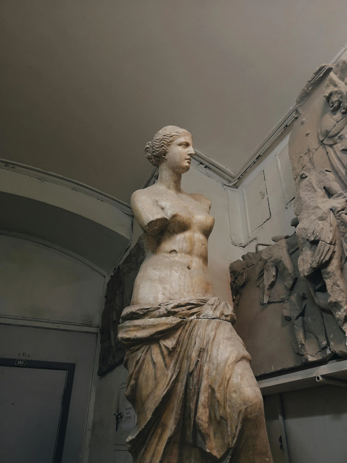 The Venus de Milo statue, a famous ancient Greek sculpture of Aphrodite, displayed in a museum setting.