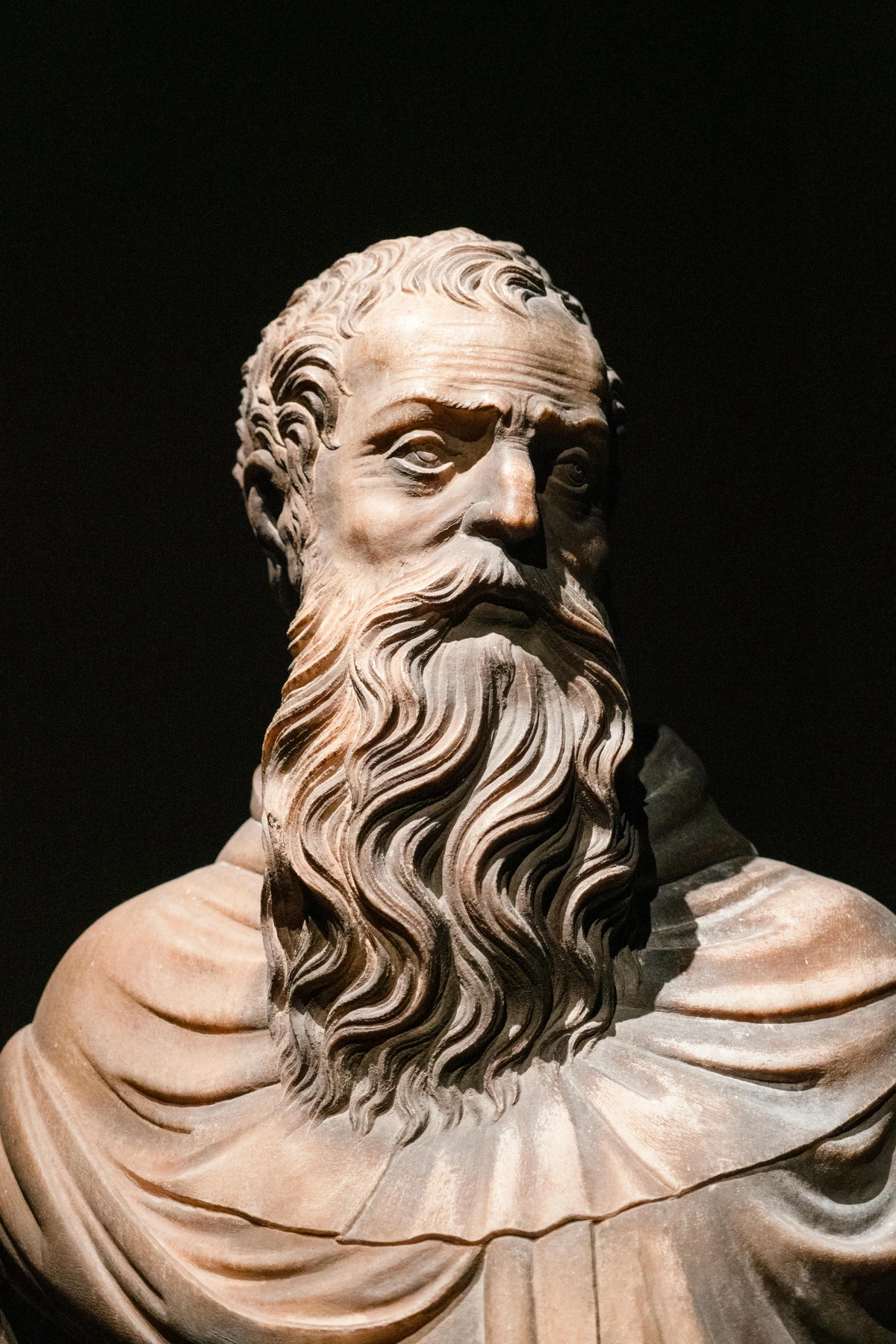 Bronze sculpture of a bearded man against a black background, symbolizing timeless artistry