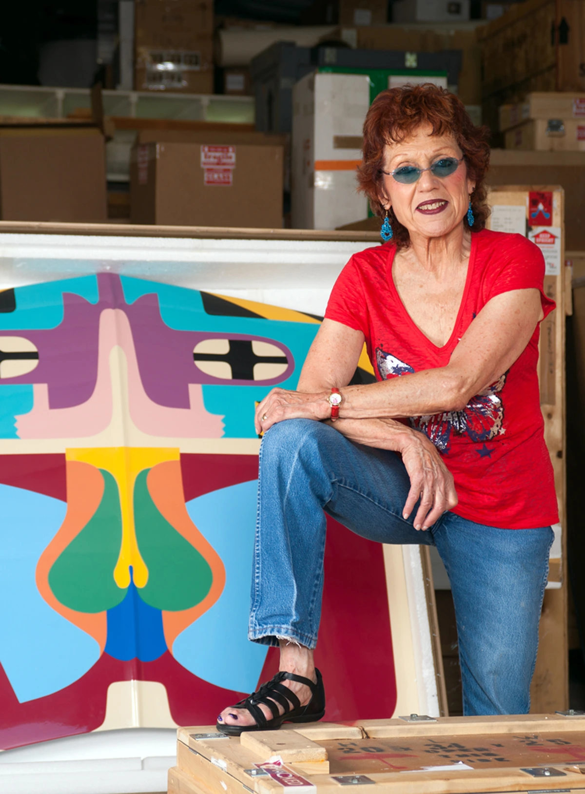 Judy Chicago, renowned feminist artist, poses with a colorful abstract artwork in her studio.