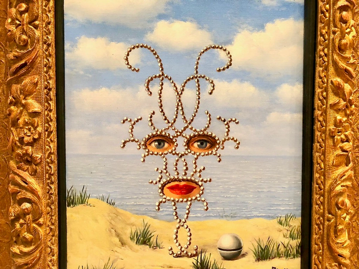 Rene Magritte's surrealist painting featuring a face made of pearls with eyes and lips, set against a beach and ocean backdrop.
