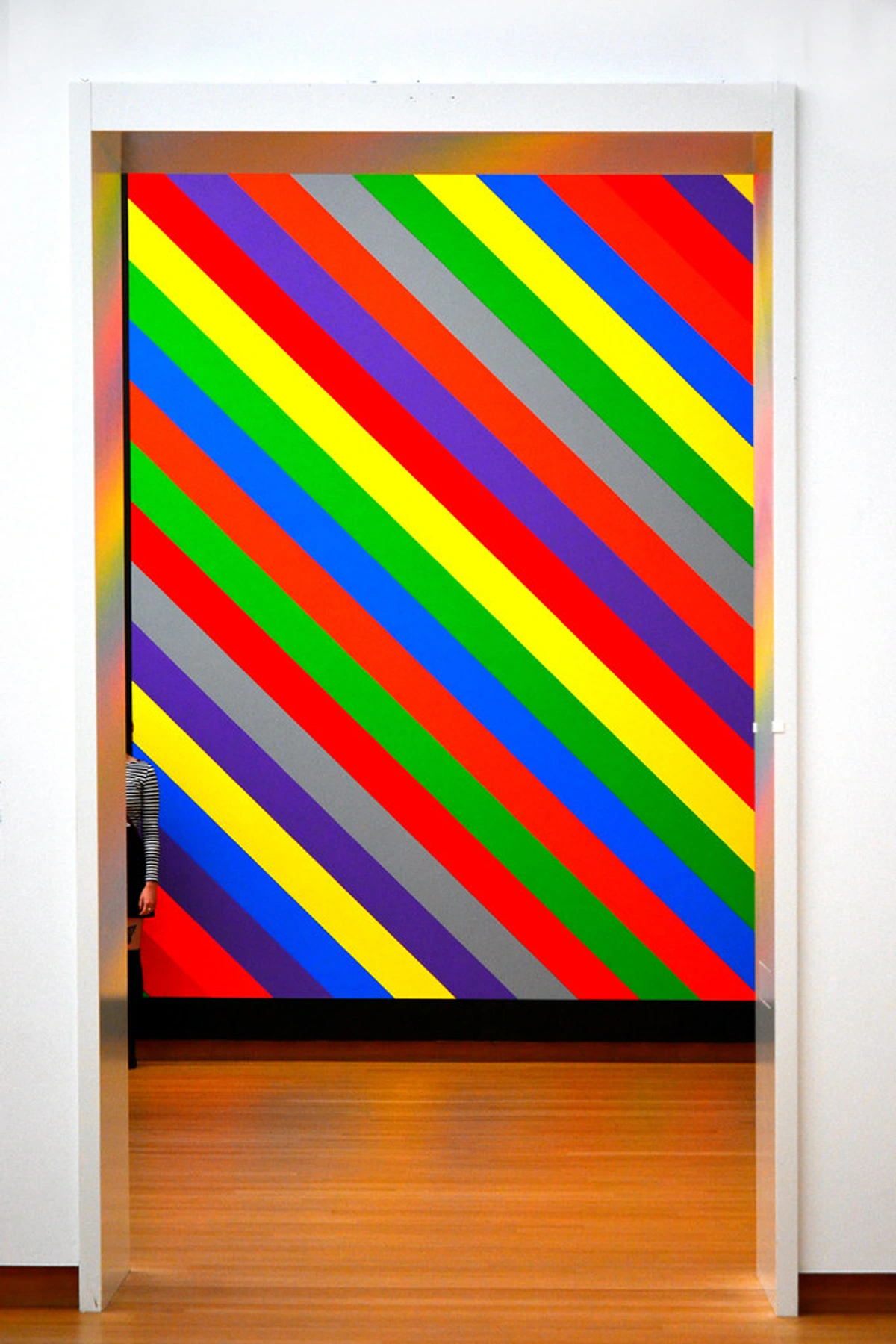 Sol LeWitt's 2003 wall drawing featuring colorful diagonal stripes of red, blue, gray, yellow, and purple against a white wall.