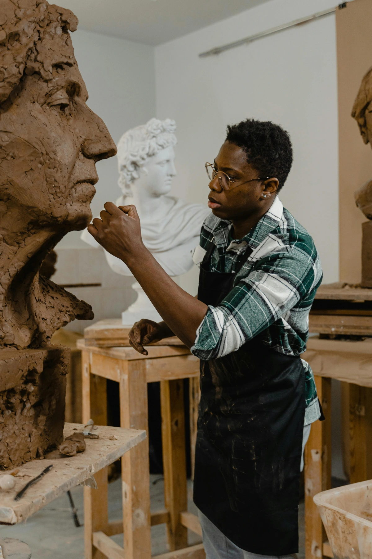 A focused man crafting a clay sculpture, illustrating the process and purpose of creating art