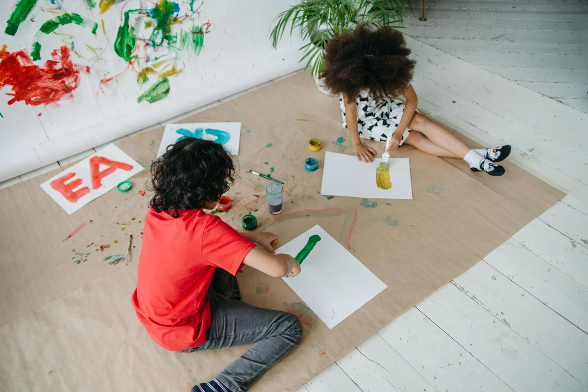 Two children painting on white paper during a creative art activity