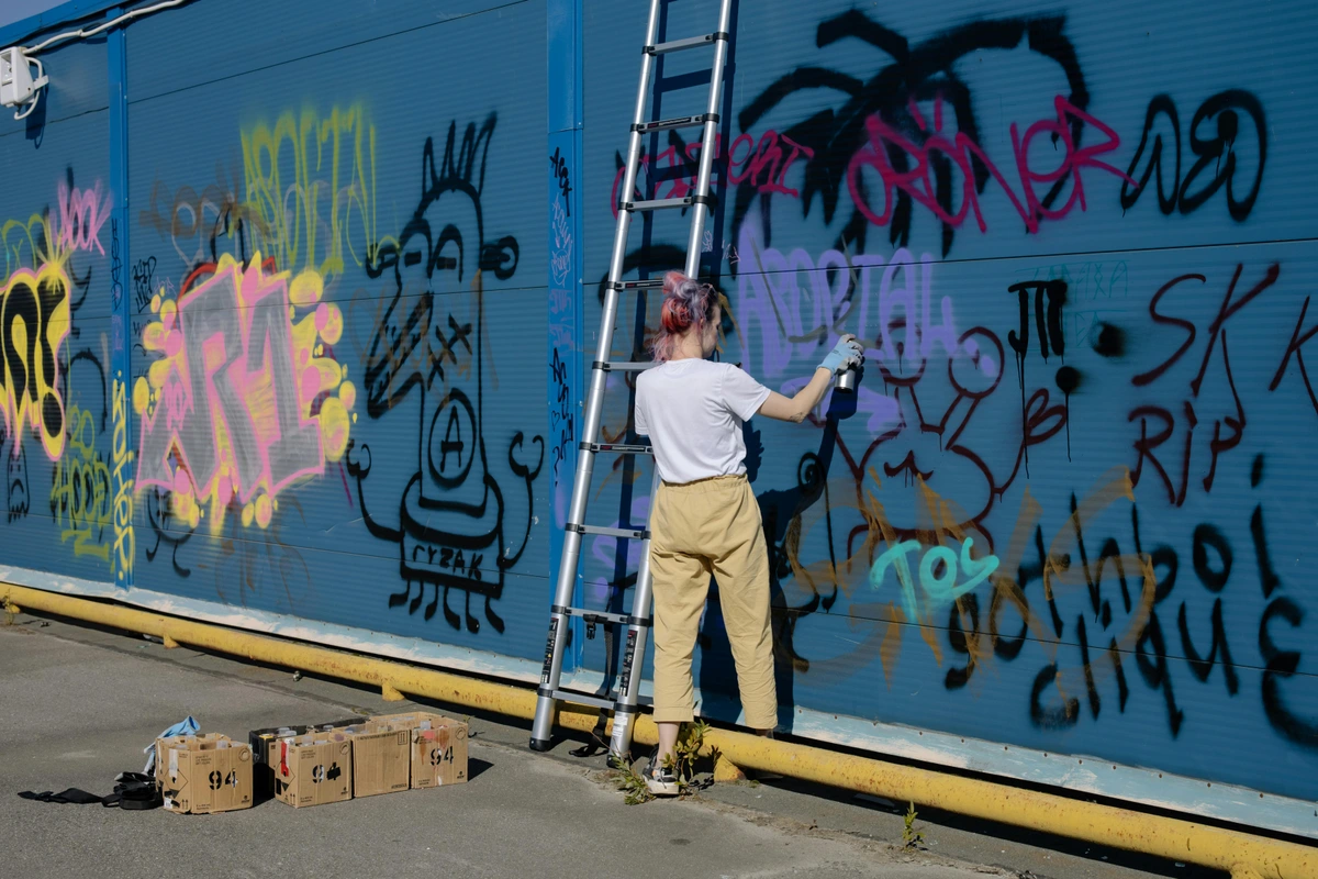 Woman Creating Graffiti Art on Blue Wall Free Stock Photo Expressing Art Meaning Purpose Sustainably Khos Ray 120246 ID 193003593 Shutterstock - Free stock photo showing artistic expression and cultural impact of graffiti art in urban environments highlighting the junction of creativity and societal engagement through modern mural installations. Art demo with vibrant graffiti lettering and character design for creative process insights social media sharing ethical art use included.
