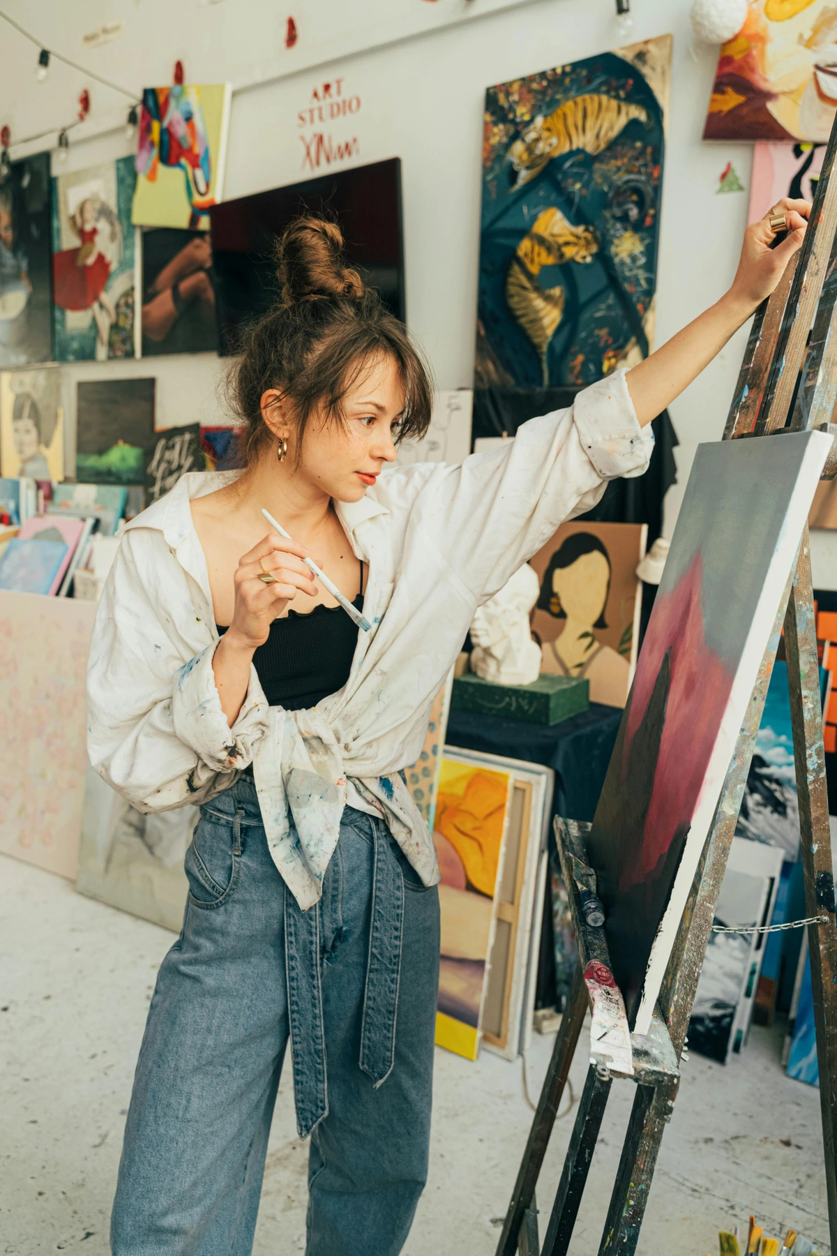 A woman focused on painting with brush in hand, symbolizing artistic purpose and creative expression in an art studio setting.