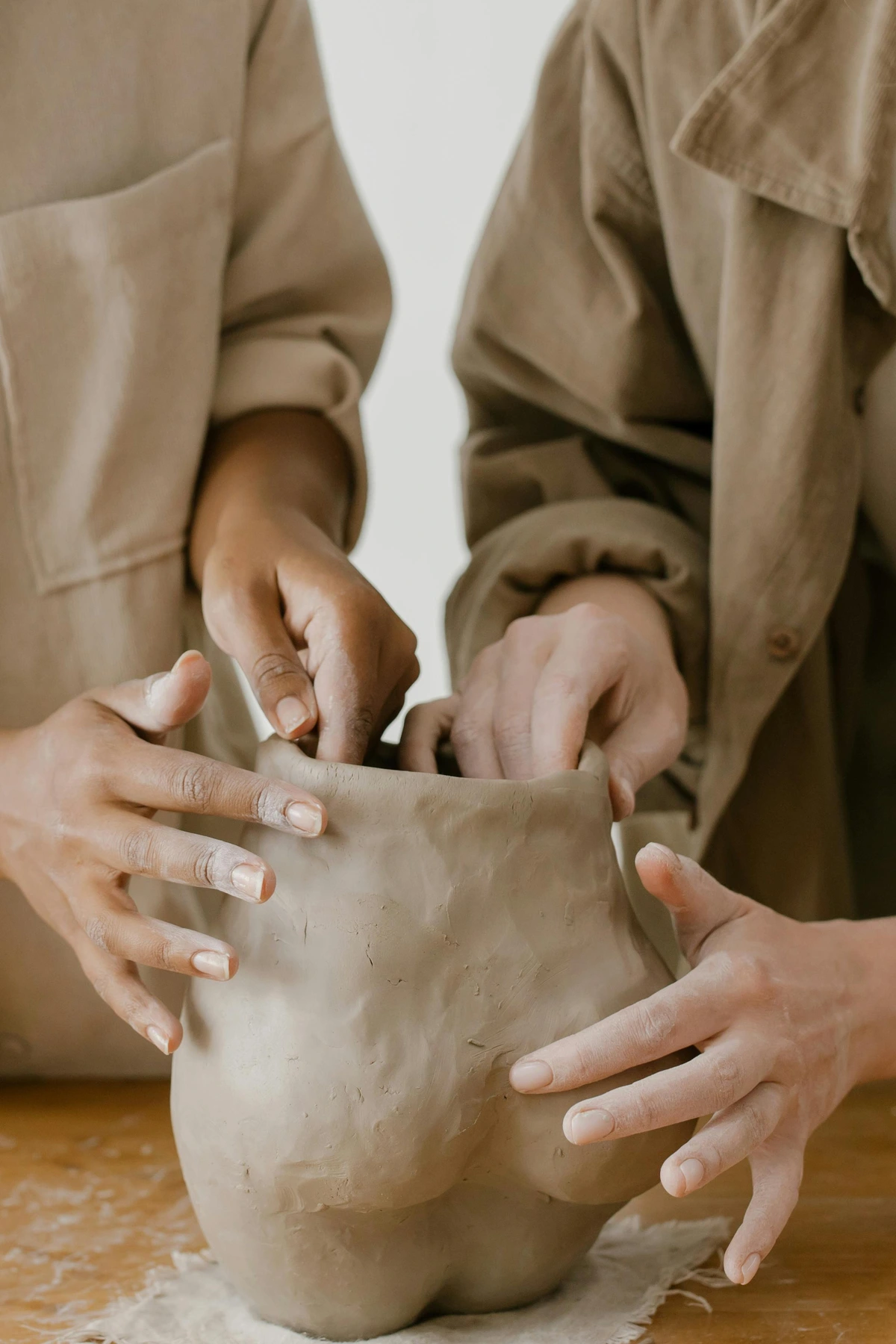 Two people sculpting clay together, highlighting creativity and partnership in art creation.
