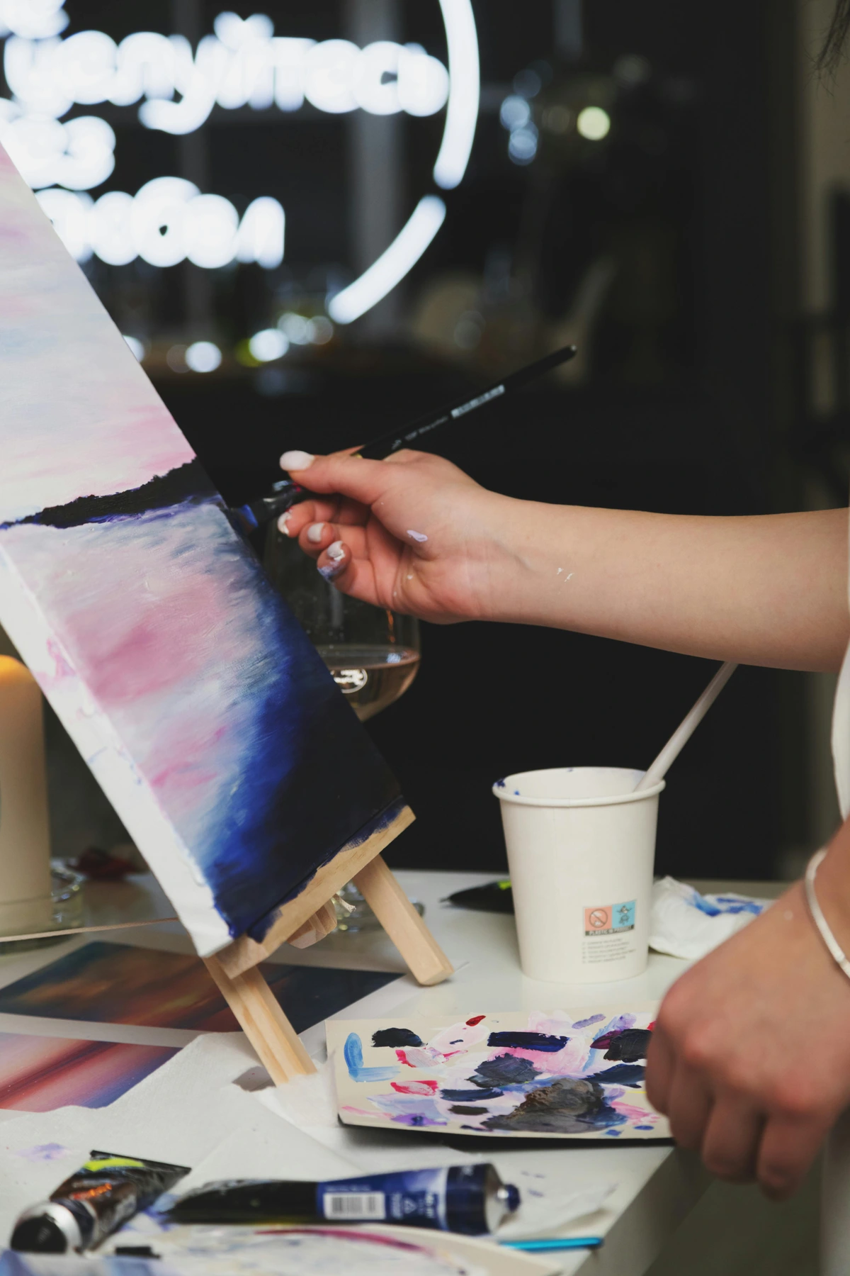 Close-up of a woman artist painting on canvas, exploring the meaning and purpose of art through emotional color blending.