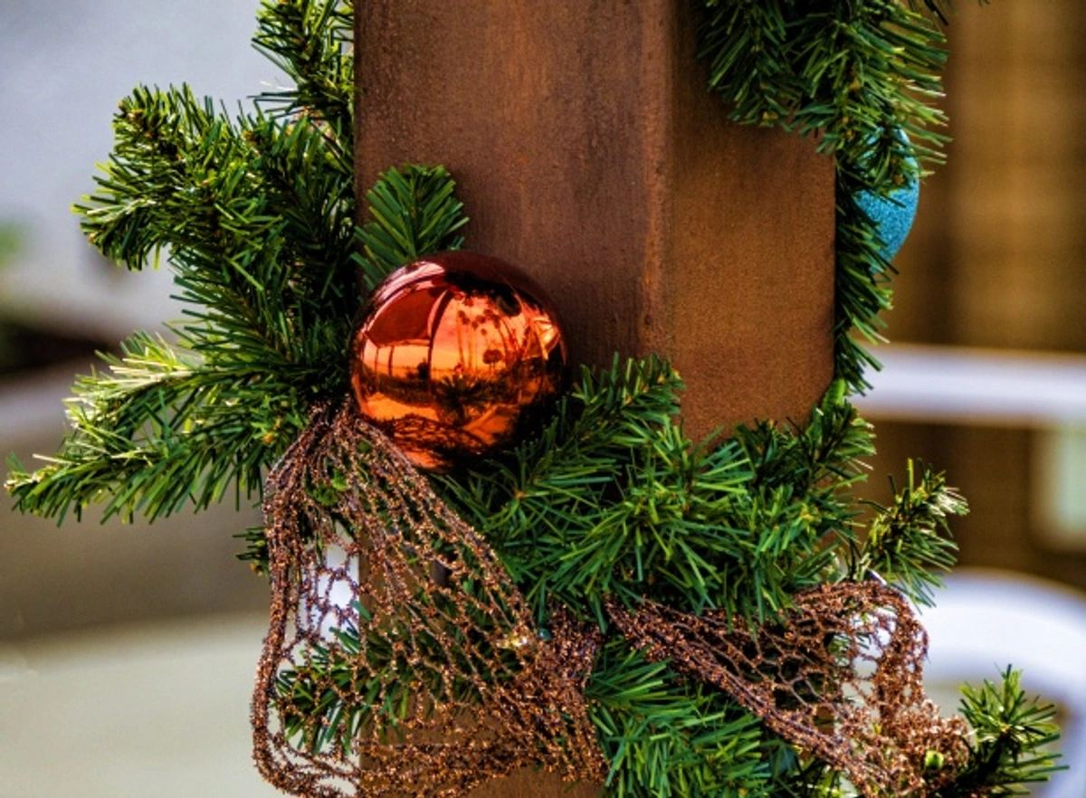 Patio post decorated with Christmas garland, copper bauble, and mesh ribbon