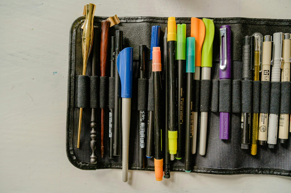 A collection of colorful pens and calligraphy tools neatly organized in a black case, showcasing a variety of writing instruments.