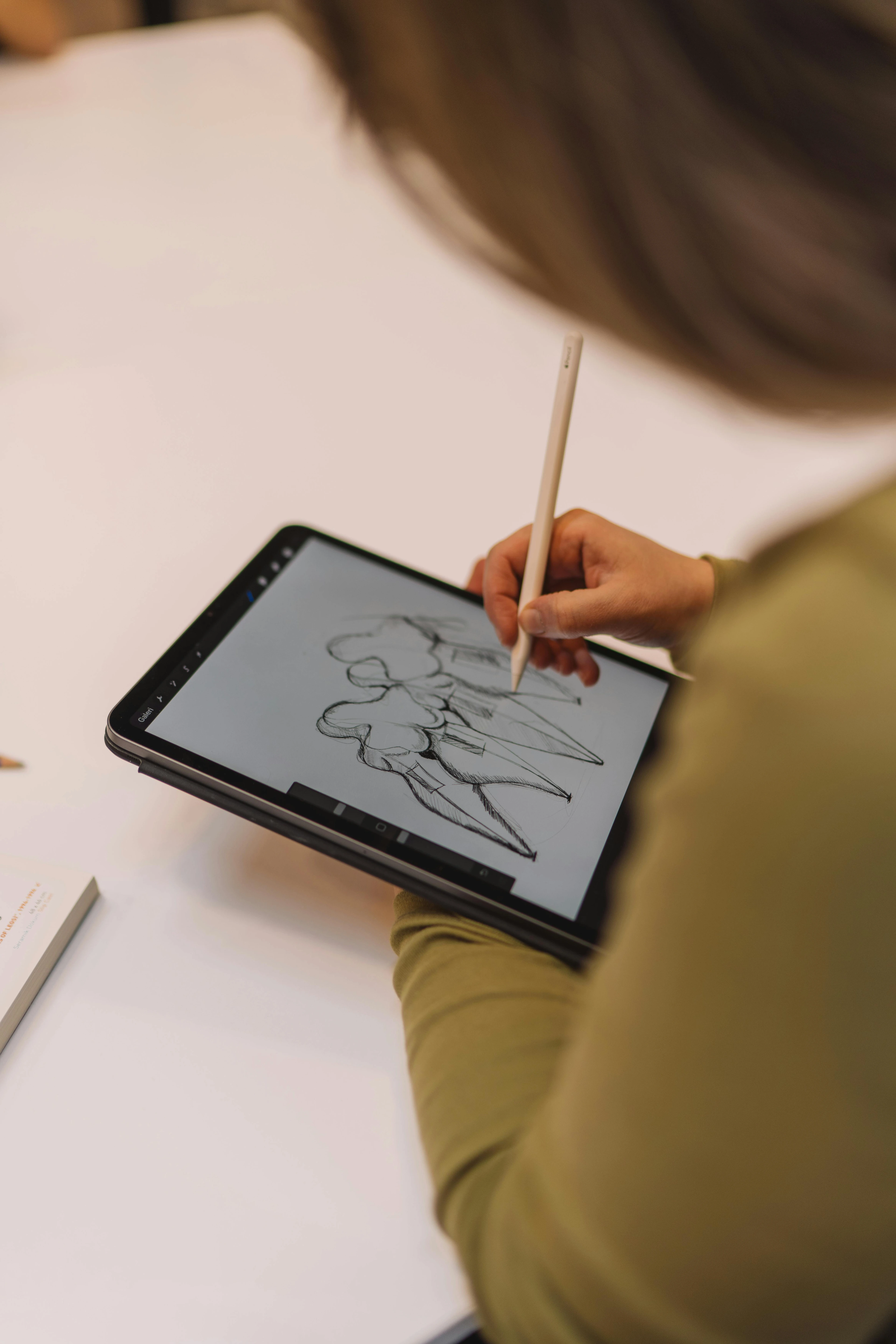 Woman sketching on a digital drawing tablet with a stylus, showcasing essential tools for digital painting beginners.