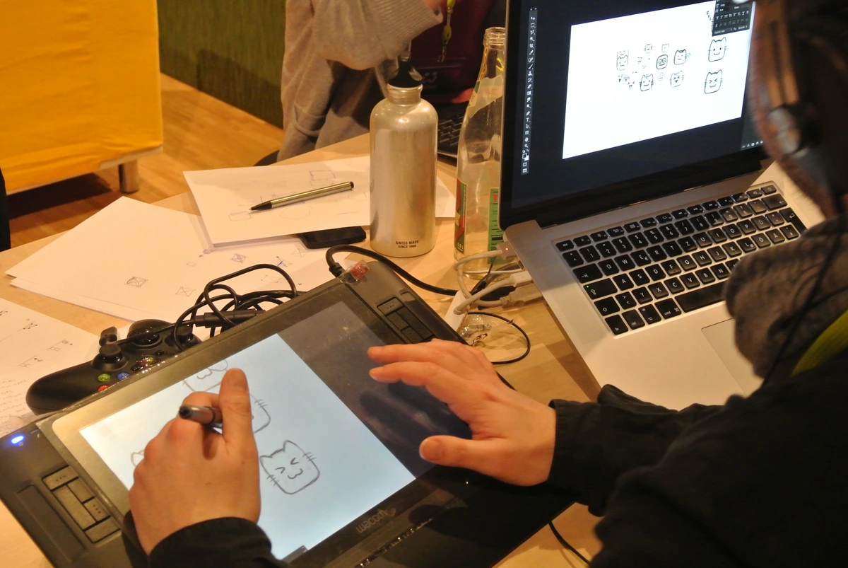 Drawing cats on a Wacom Intuos3 A5 graphics tablet connected to a laptop, with a pen and a water bottle nearby.