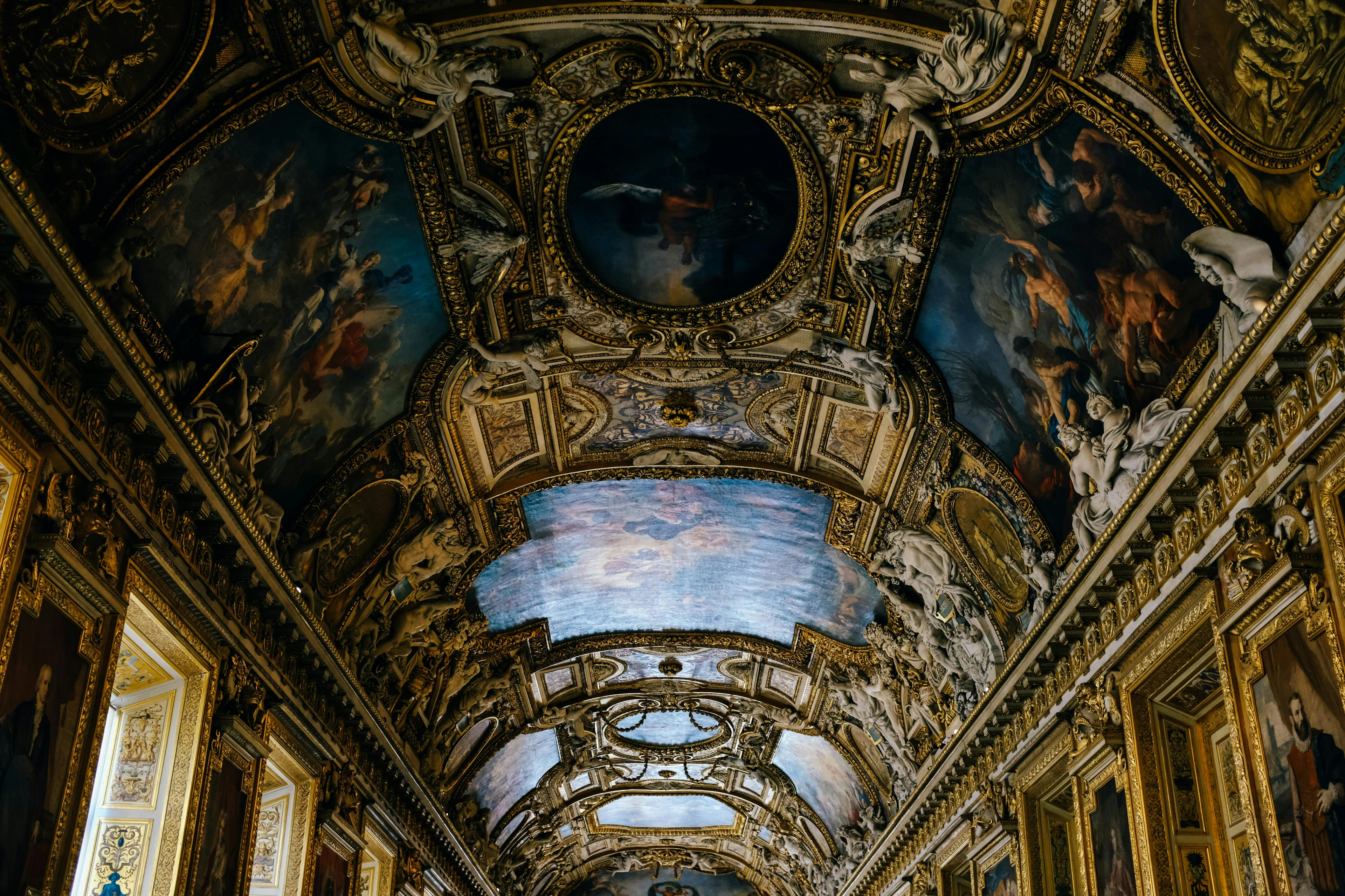 Intricate golden carvings and painted ceilings inside the Louvre Museum in Paris, France.